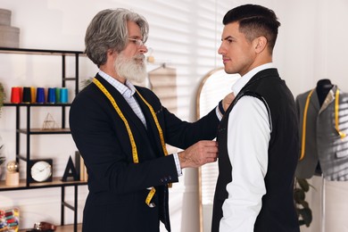 Photo of Professional tailor working with client in atelier