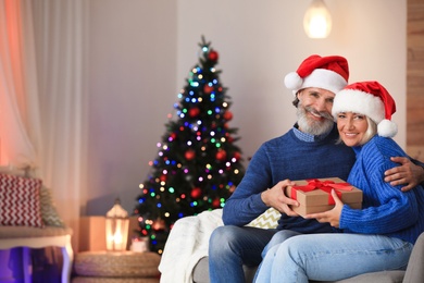 Happy couple opening Christmas gift at home