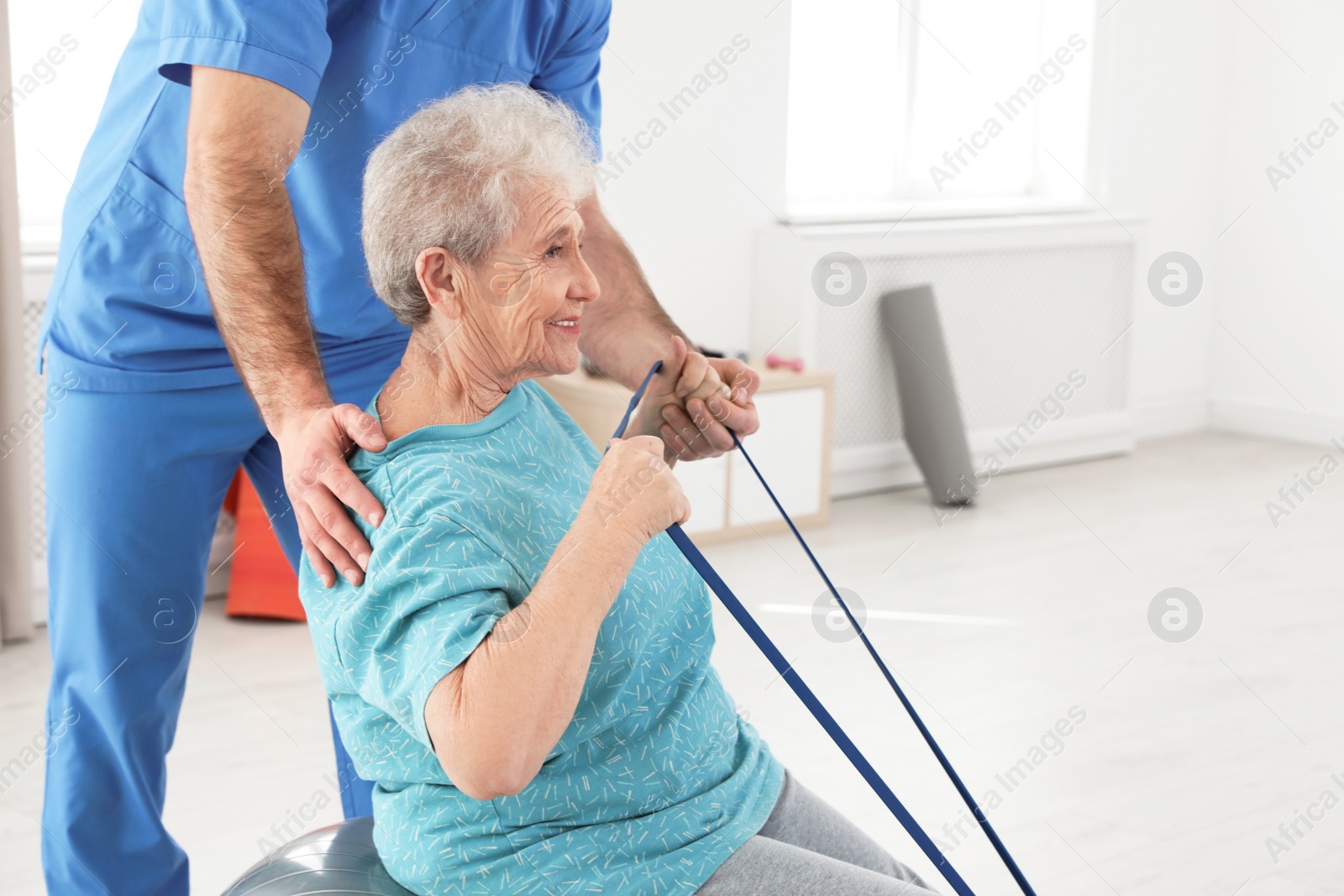 Photo of Professional physiotherapist working with elderly patient in rehabilitation center. Space for text