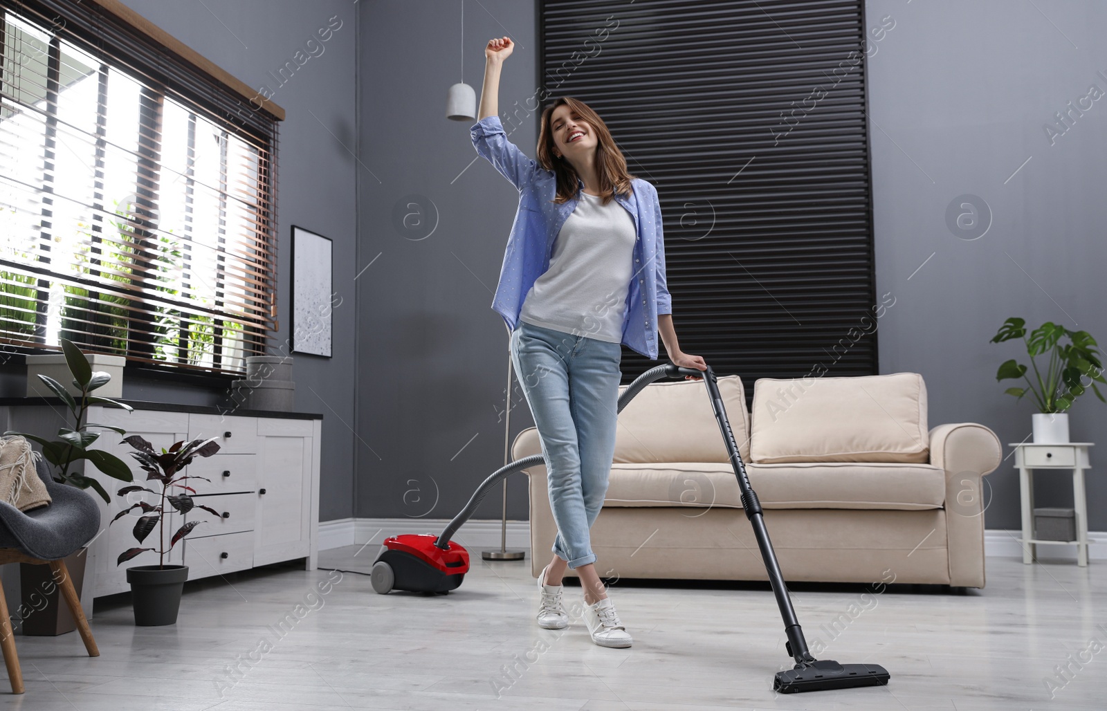 Photo of Young woman having fun while vacuuming at home