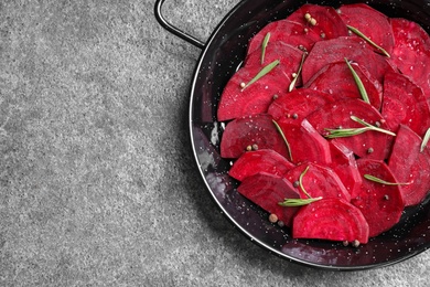 Photo of Slices of raw beetroot in wok pan on grey table, top view. Space for text