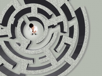 Image of Businessman trying to find way out of maze, above view