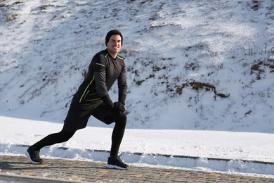 Photo of Man doing sports exercises outdoors on winter day. Space for text