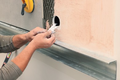 Photo of Worker installing socket in tile indoors, closeup