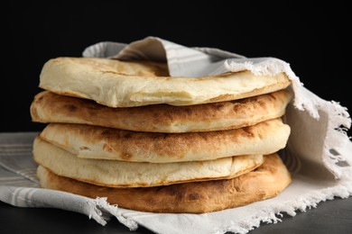 Delicious fresh pita bread with napkin on black table