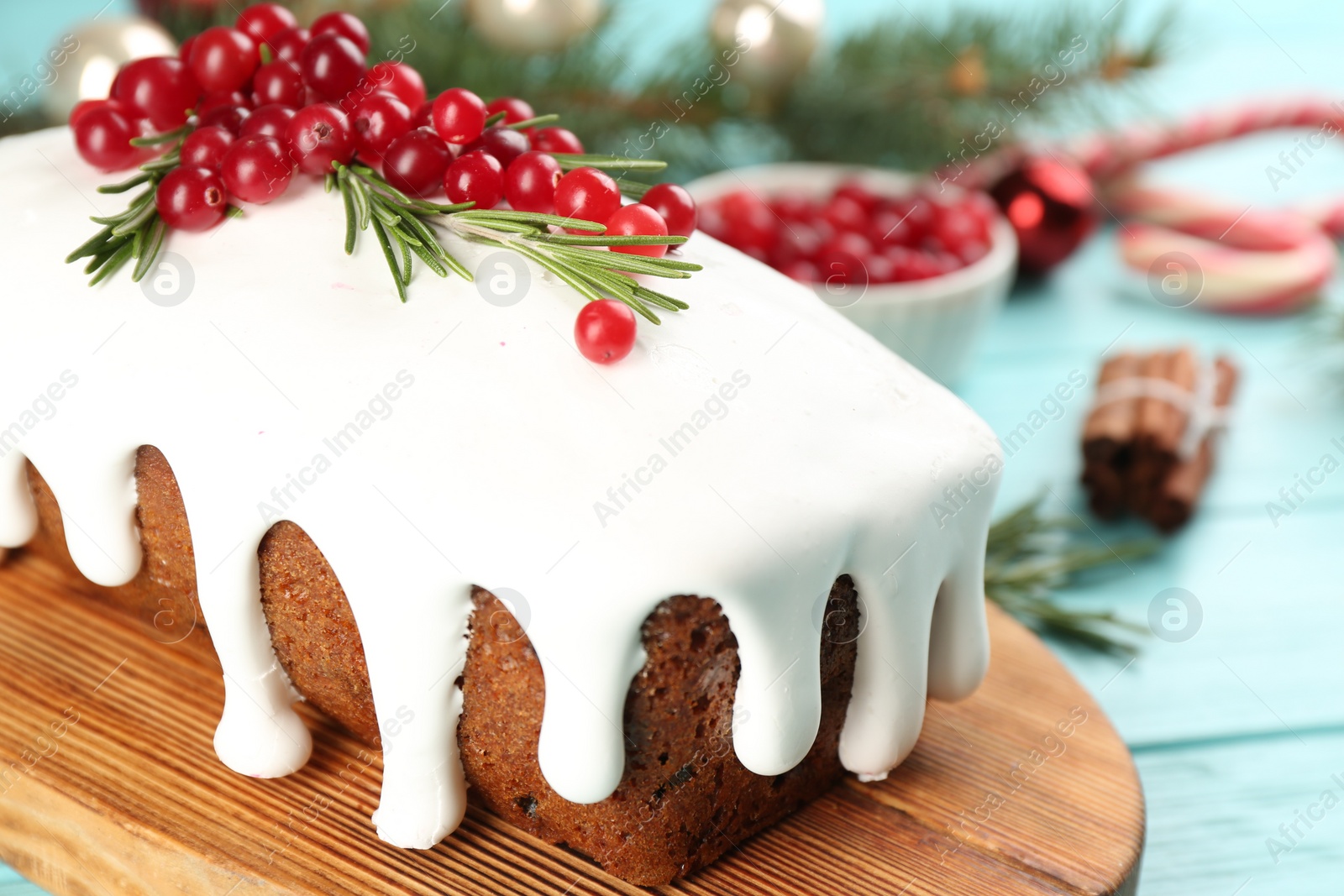 Photo of Traditional classic Christmas cake decorated with cranberries and rosemary on turquoise table, closeup