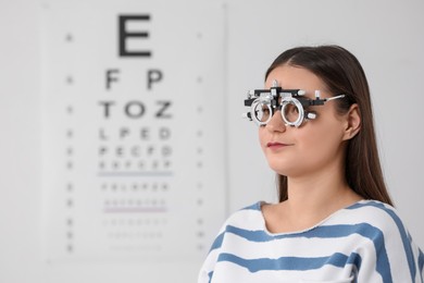 Photo of Young woman with trial frame against vision test chart