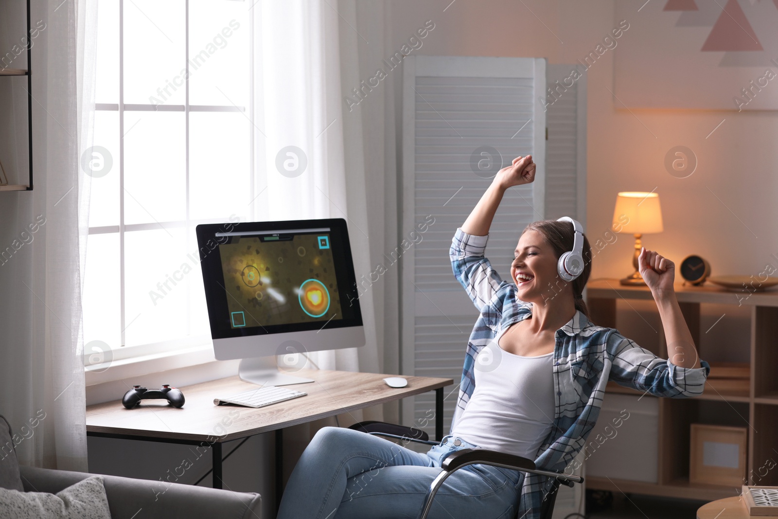 Photo of Emotional young woman playing video games at home