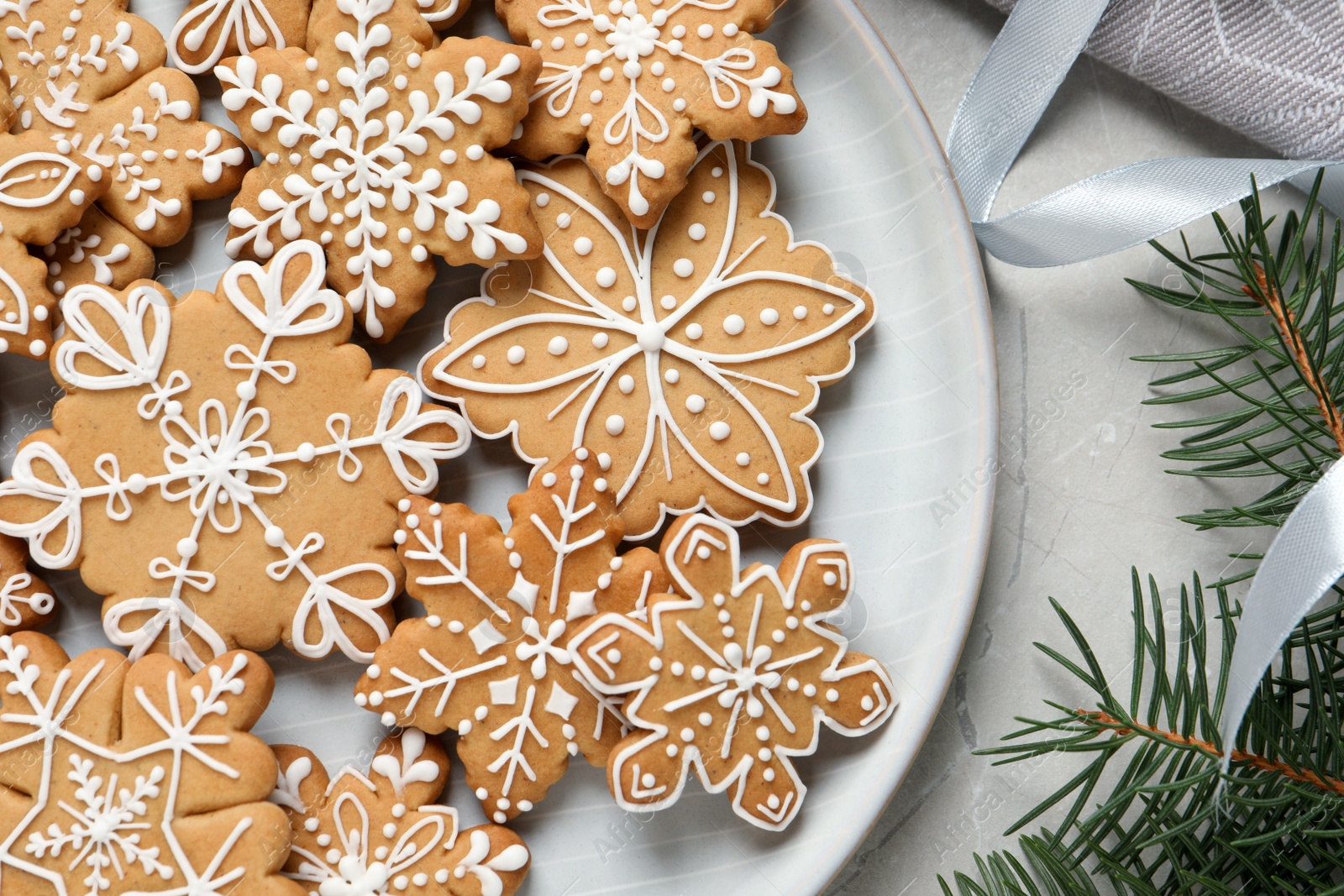 Photo of Tasty Christmas cookies and fir branches on light grey table, flat lay