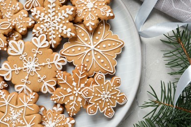 Tasty Christmas cookies and fir branches on light grey table, flat lay