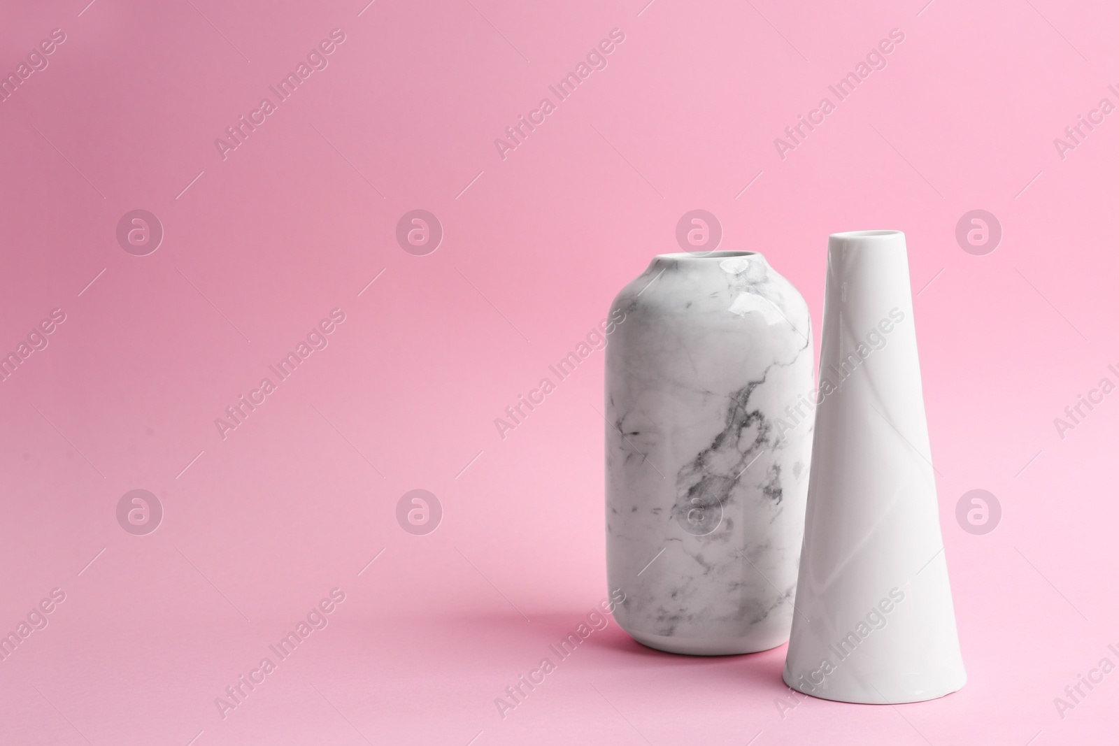 Photo of Stylish empty ceramic vases on pink background. Space for text