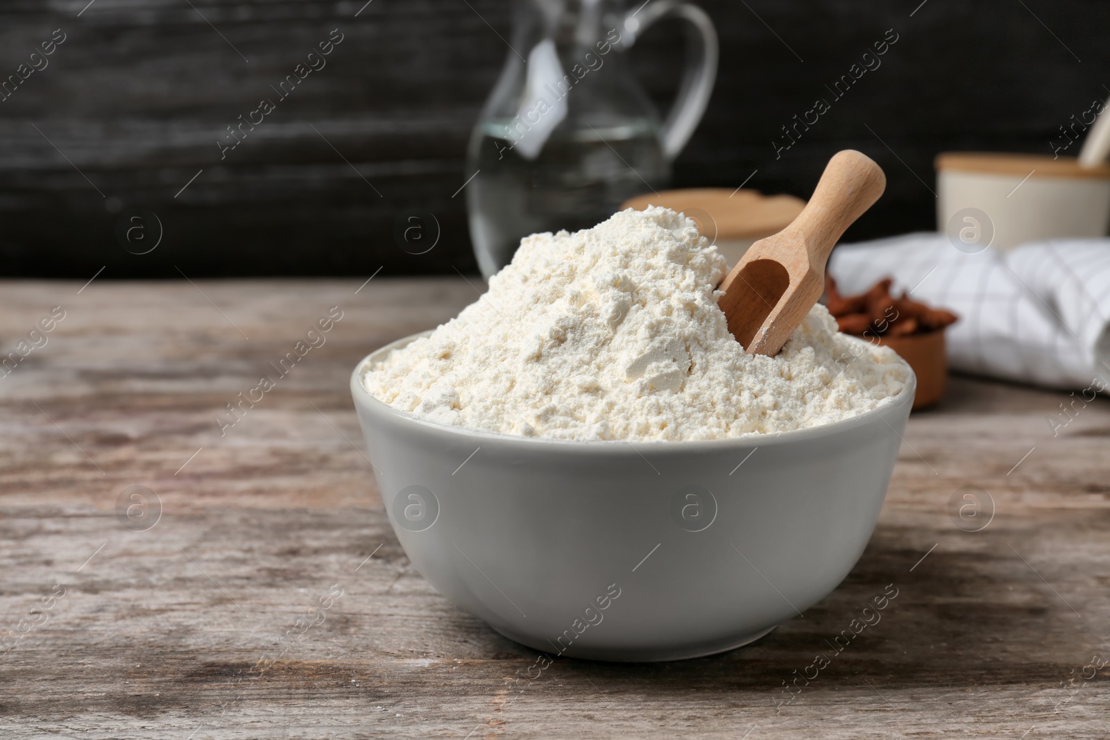 Photo of Bowl and scoop with flour on wooden table