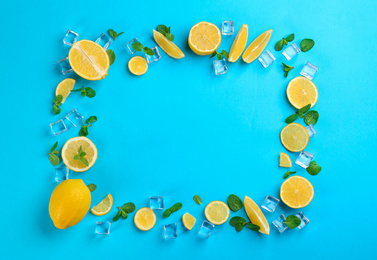 Photo of Frame made of lemon slices, mint and ice on blue background, top view with space for text. Lemonade layout