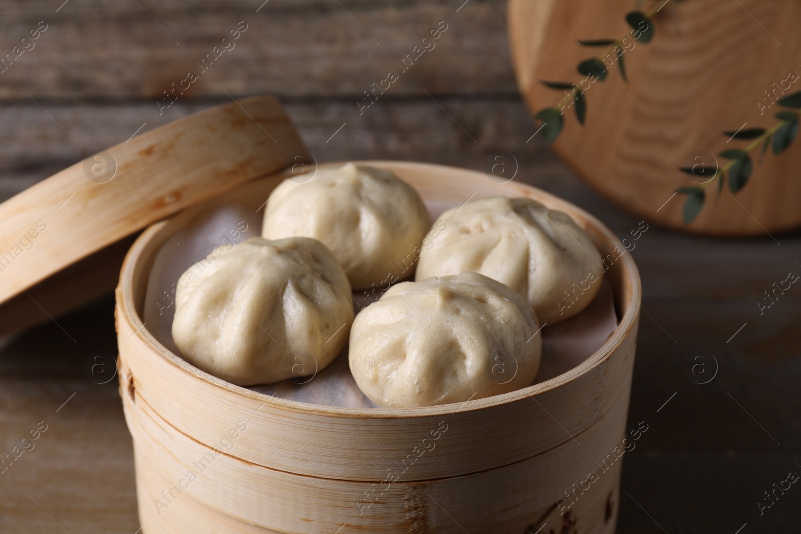 Photo of Delicious bao buns (baozi) on wooden table, closeup