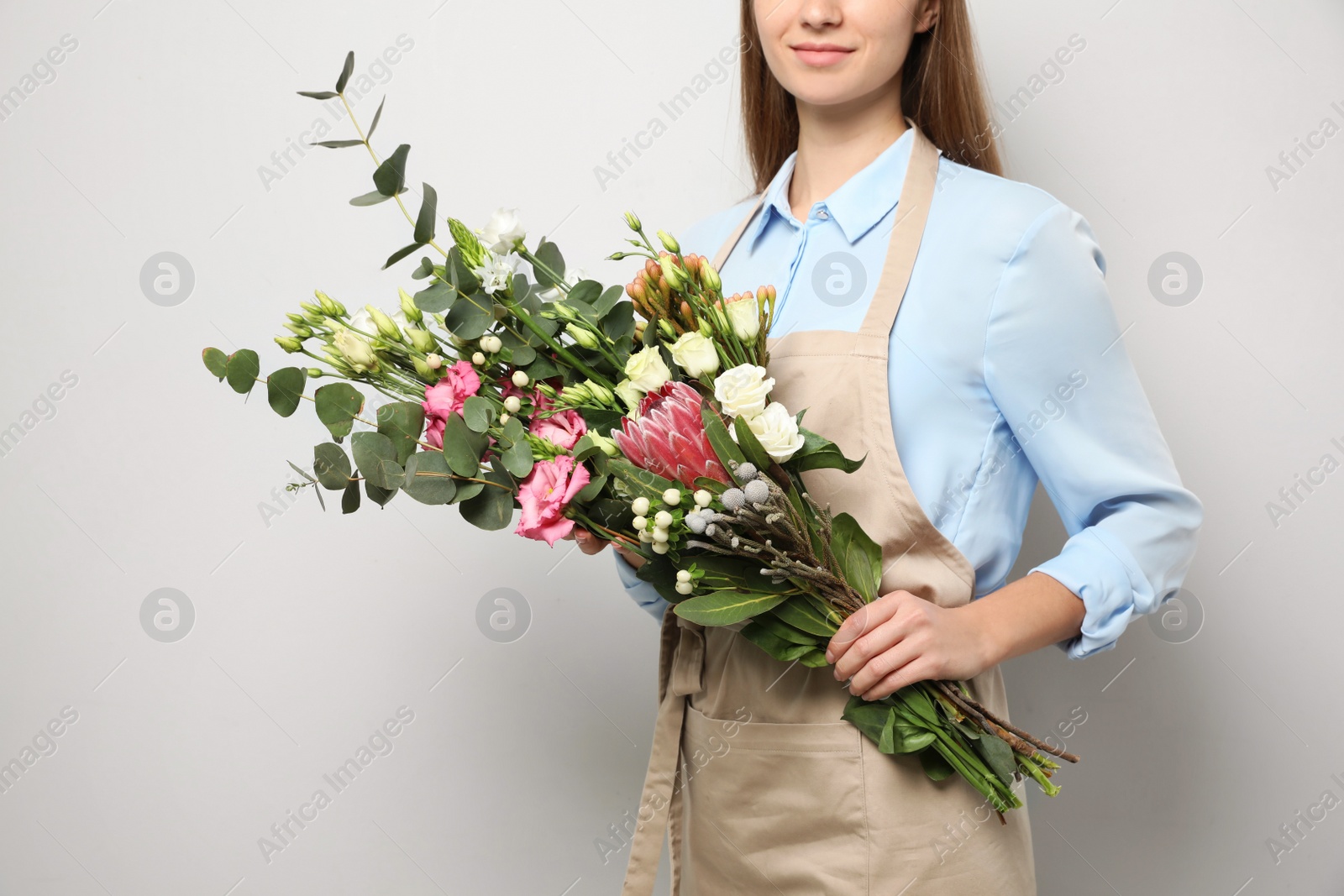 Photo of Florist with beautiful bouquet on light background, closeup