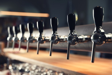 Photo of Row of shiny beer taps in pub, closeup