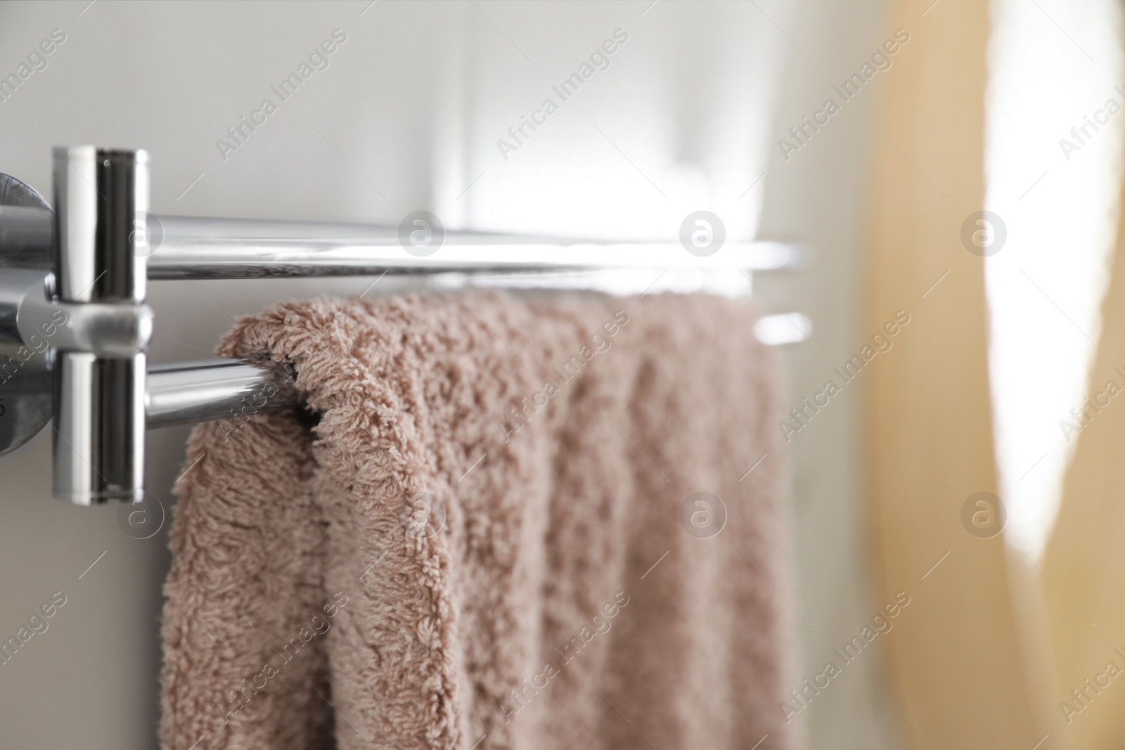 Photo of Holder with clean towel on light wall in bathroom, closeup