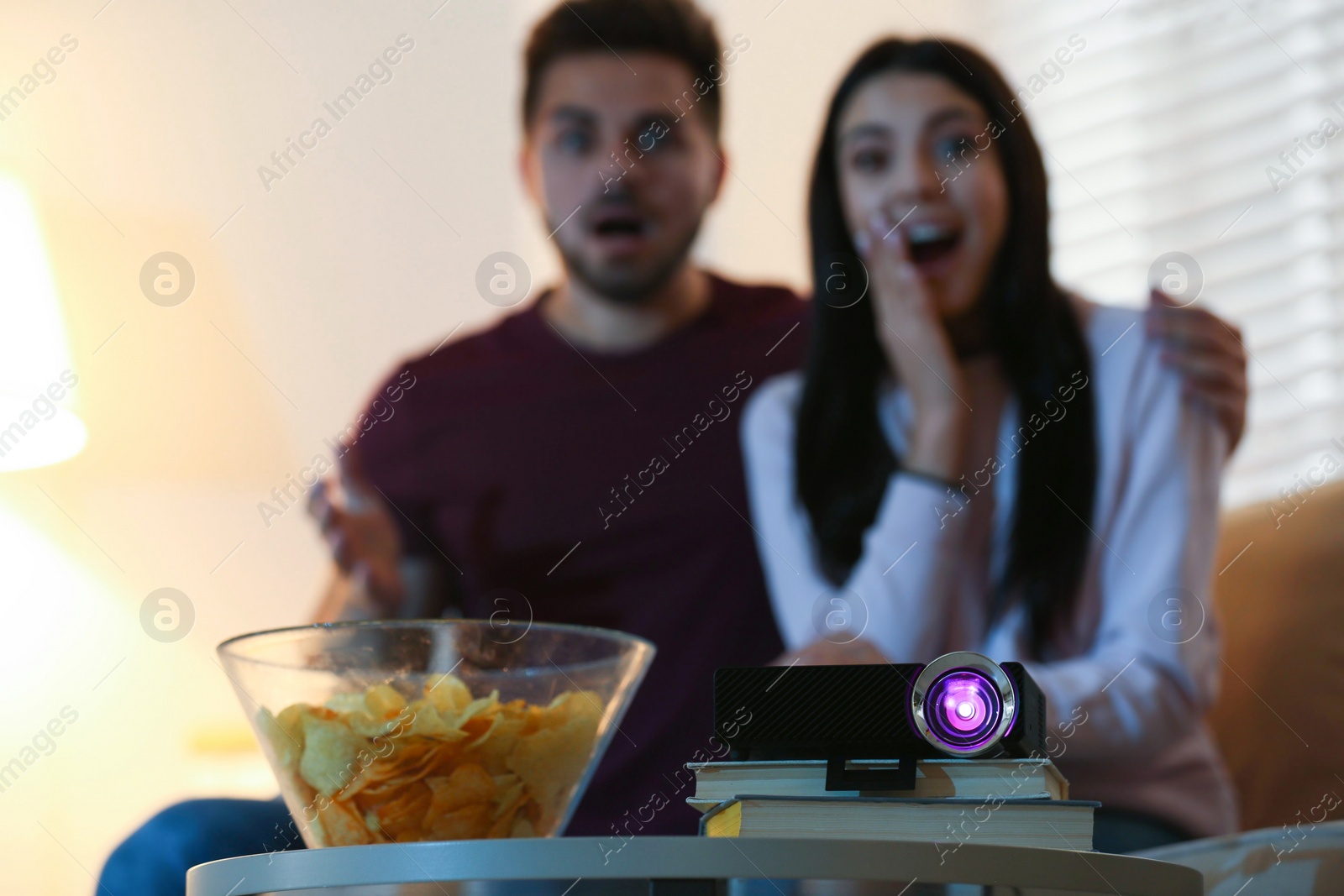 Photo of Young couple watching movie at home, focus on video projector