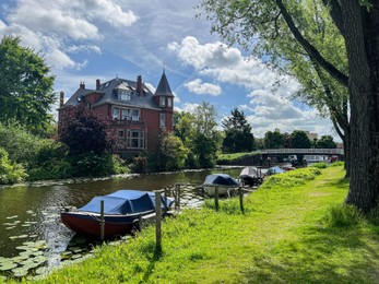 Beautiful view of house near river with moored boats on sunny day