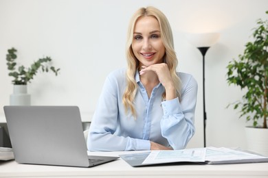 Happy secretary at table with laptop in office