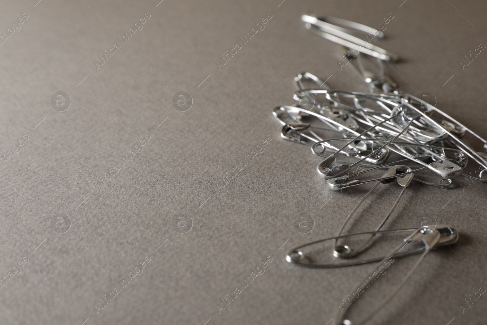 Photo of Safety pins on grey textured background, closeup. Space for text