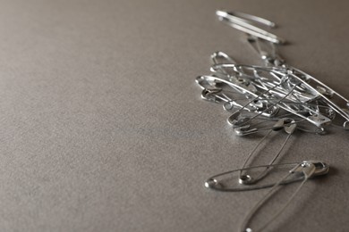 Photo of Safety pins on grey textured background, closeup. Space for text