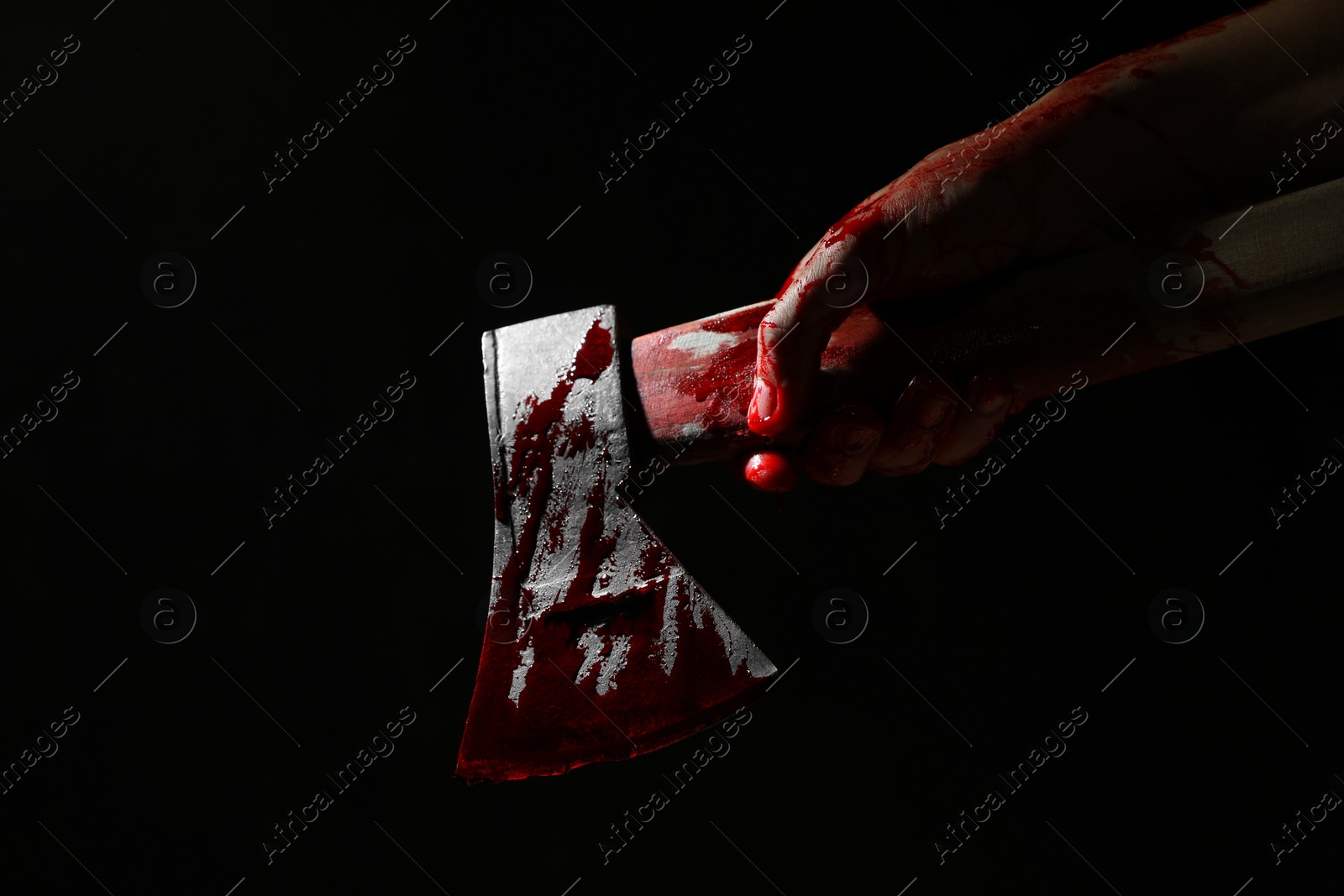 Photo of Man holding bloody axe on black background, closeup