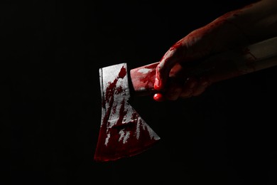 Photo of Man holding bloody axe on black background, closeup