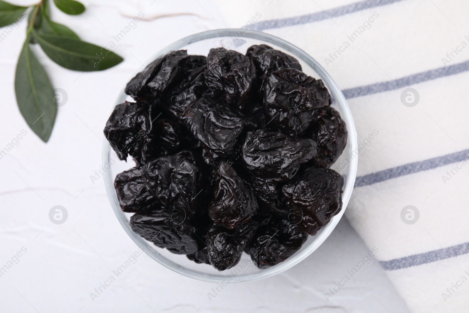 Photo of Sweet dried prunes in bowl on white table, top view