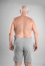 Photo of Fat senior man on grey background. Weight loss