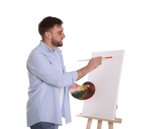 Man painting with brush on easel against white background. Young artist