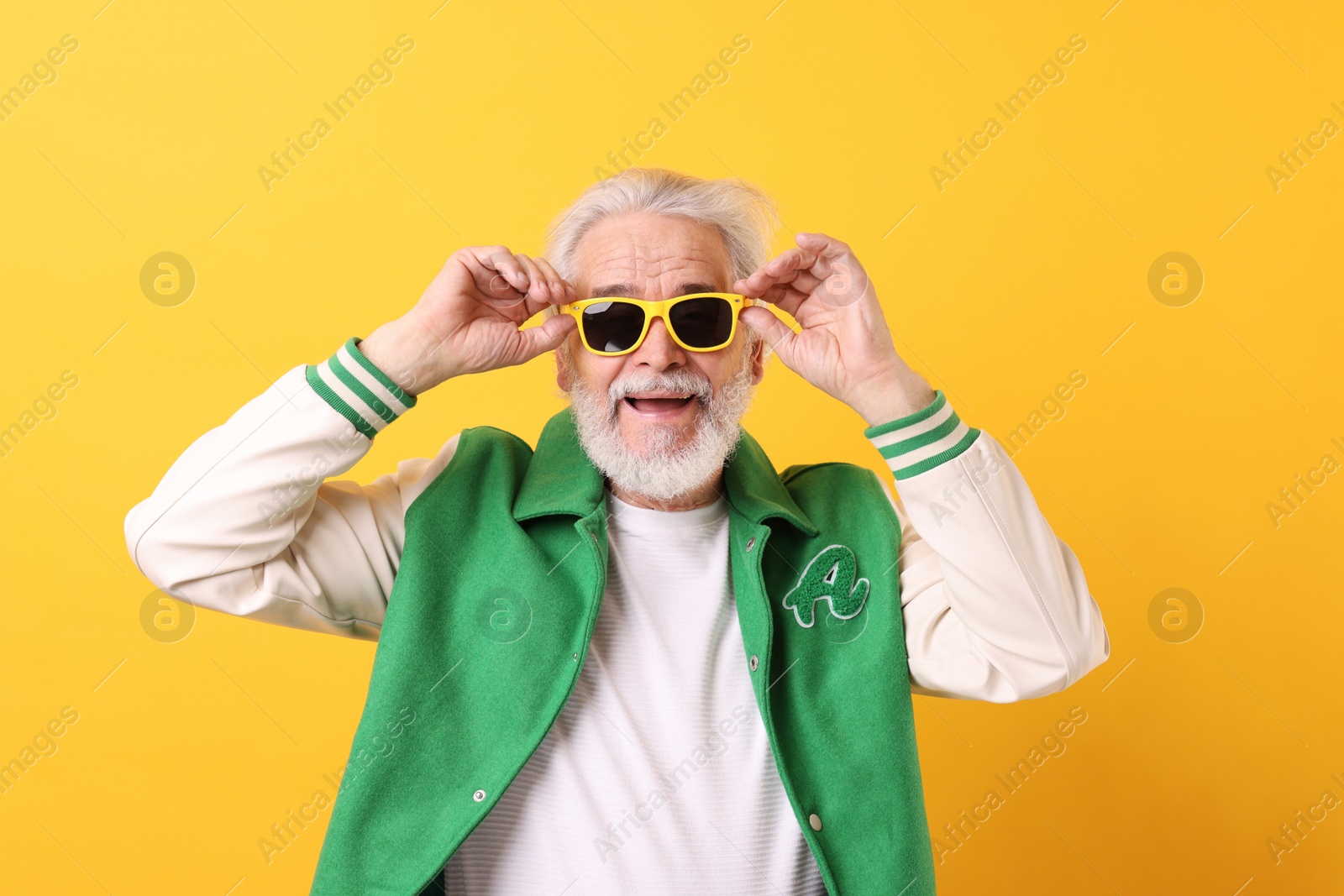 Photo of Portrait of grandpa with stylish sunglasses on yellow background