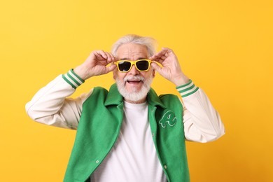 Portrait of grandpa with stylish sunglasses on yellow background