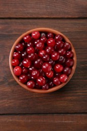 Photo of Fresh ripe cranberries in bowl on wooden table, top view