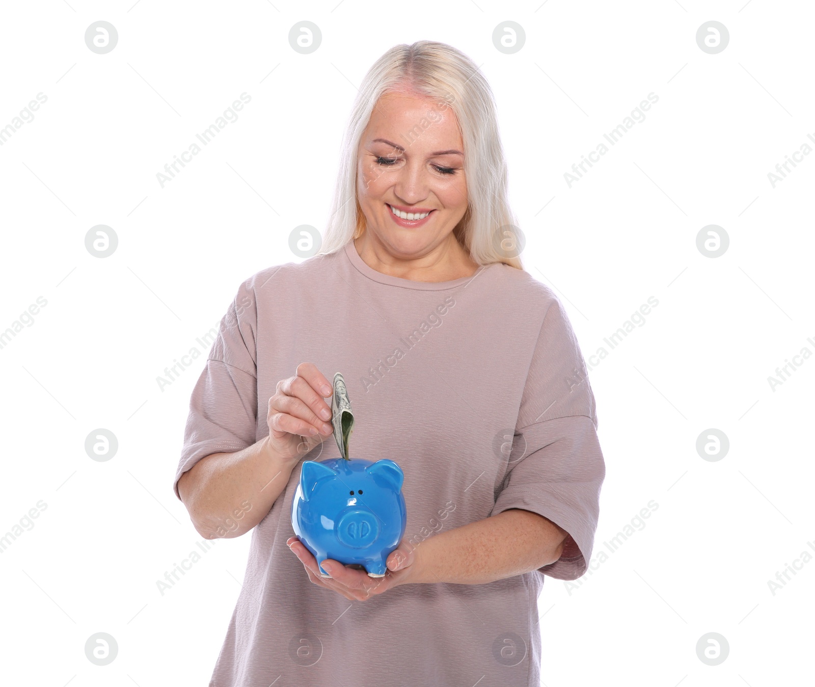 Photo of Mature woman putting money into piggy bank on white background