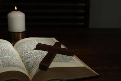 Photo of Cross, Bible and church candle on wooden table