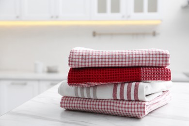 Photo of Stack of different clean towels on white table in kitchen
