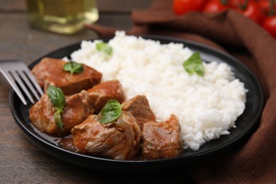Photo of Delicious goulash served with rice on wooden table, closeup