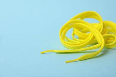 Photo of Yellow shoe lace on light blue background. Space for text