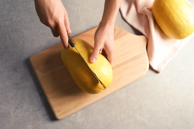 Photo of Woman cutting spaghetti squash on gray table, top view