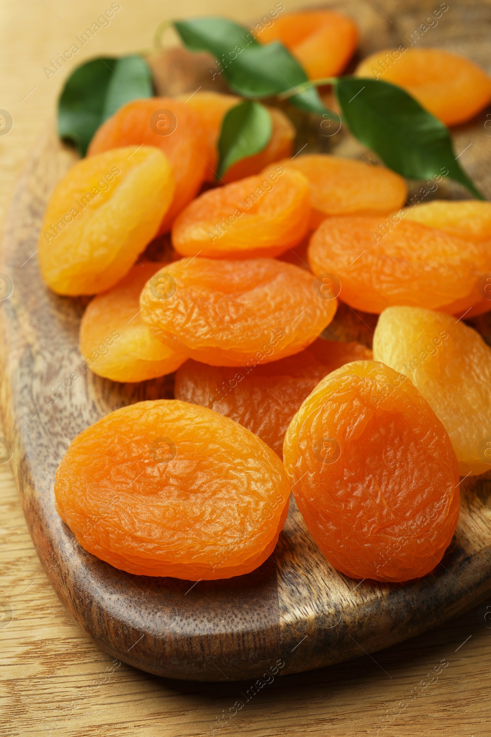 Photo of Tasty apricots on wooden table, closeup. Dried fruits