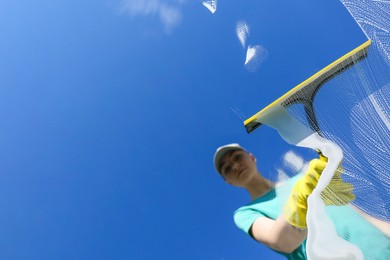 Photo of Woman cleaning glass with squeegee on sunny day