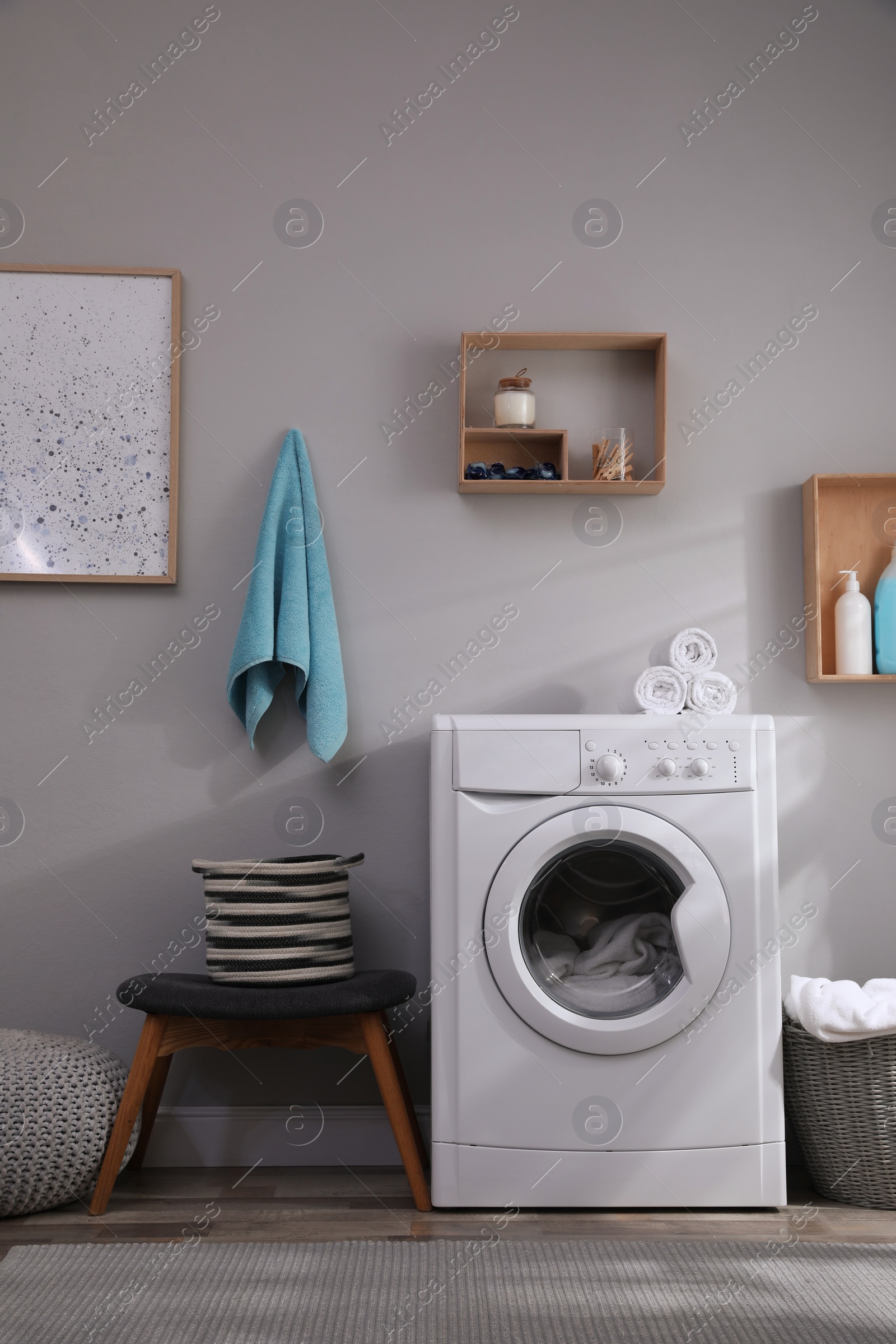 Photo of Laundry room interior with modern washing machine near light wall