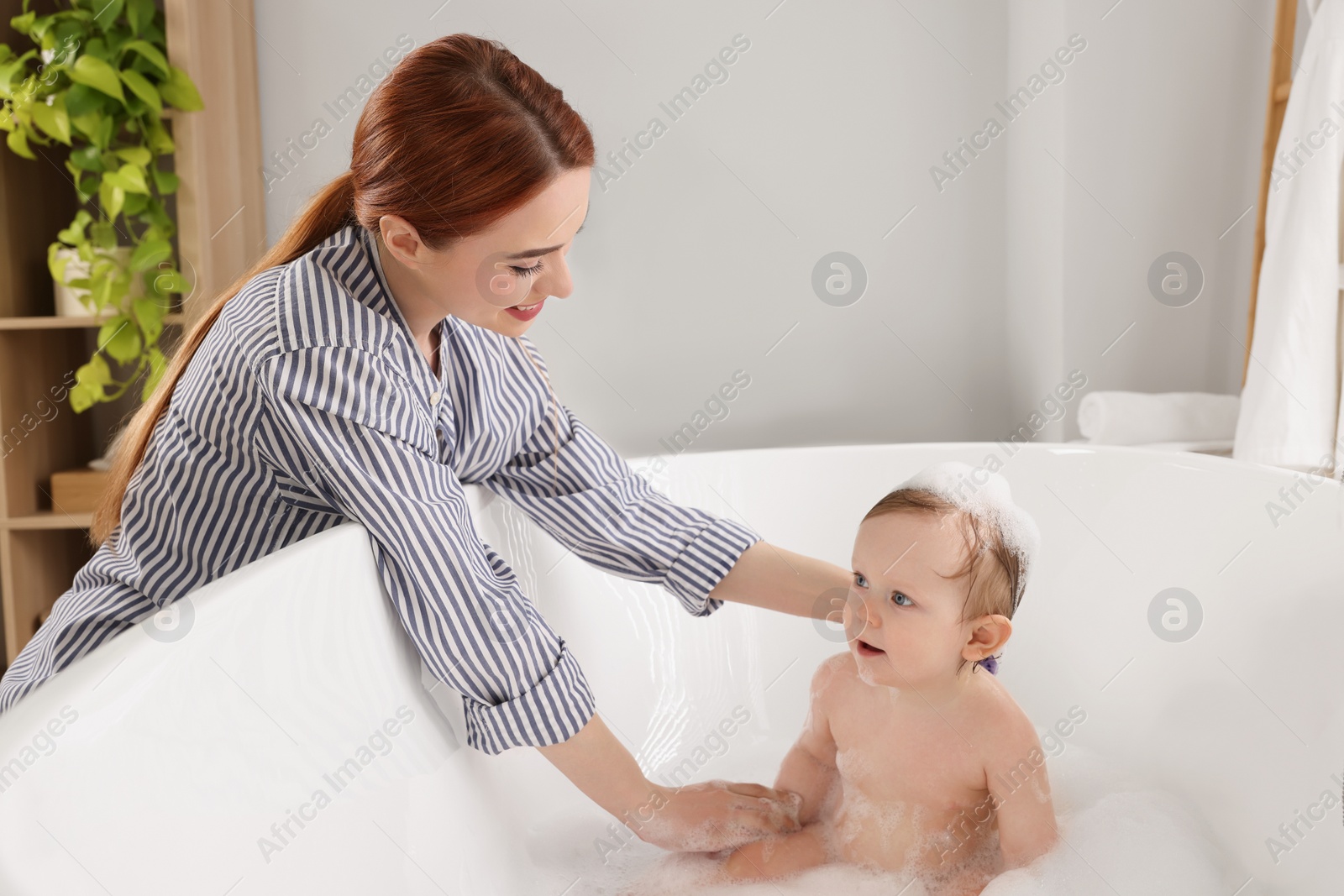 Photo of Mother washing her little baby in tub at home