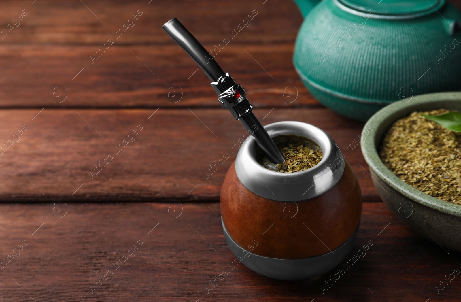 Photo of Calabash with mate tea and bombilla on wooden table. Space for text