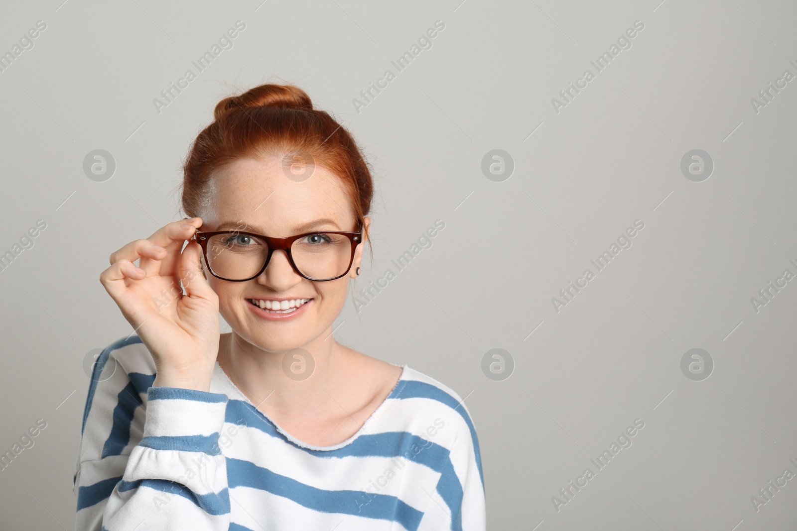 Photo of Candid portrait of happy red haired woman with charming smile on light background, space for text