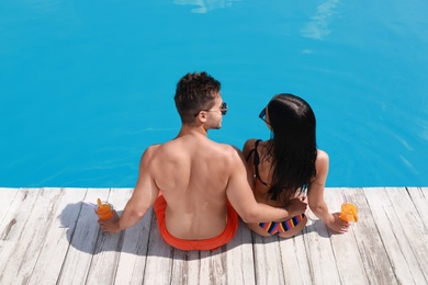 Photo of Woman in bikini with boyfriend near outdoor pool. Young couple