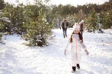 Cute little girl with her parents outdoors on winter day. Christmas vacation