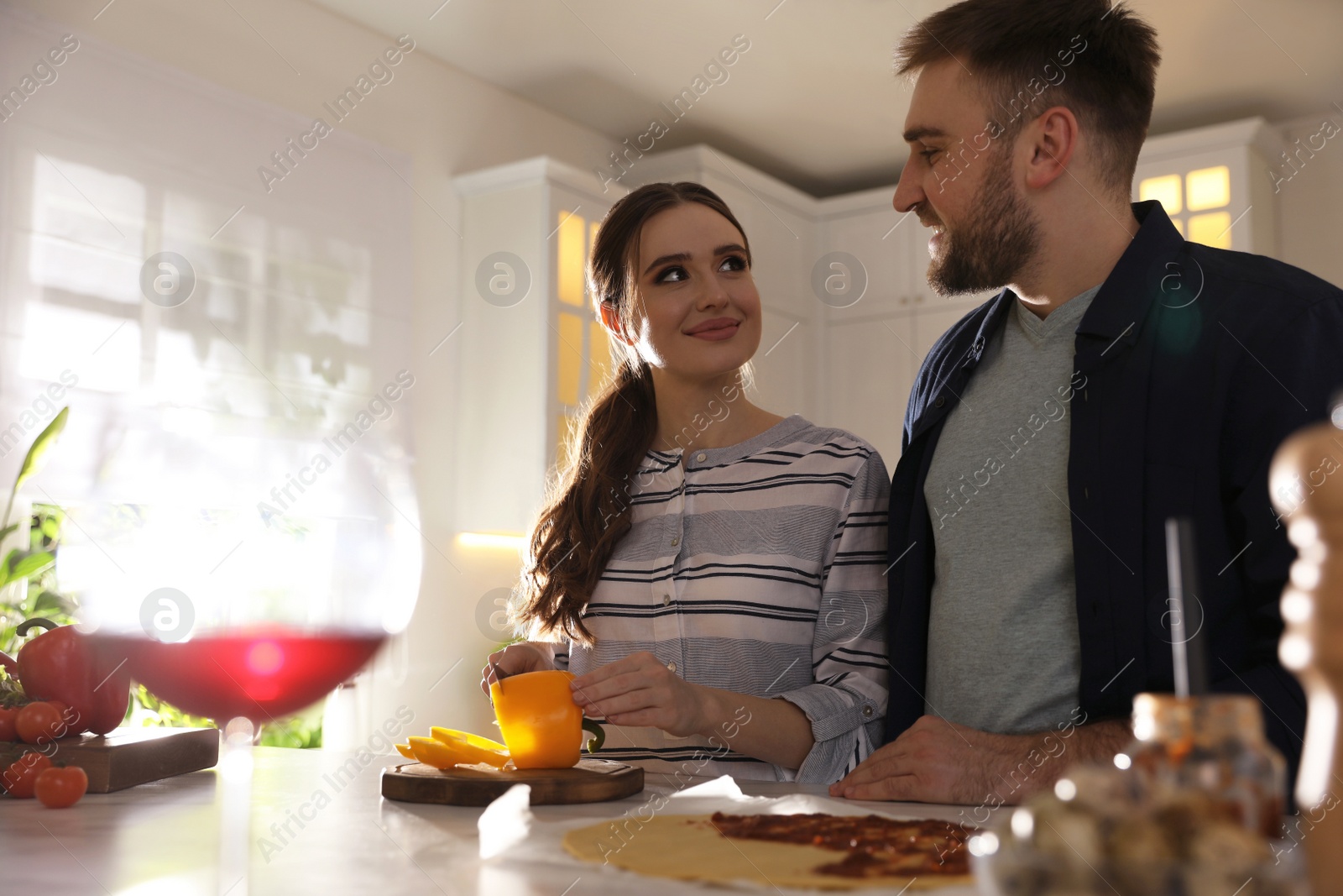 Photo of Lovely young couple cooking pizza together in kitchen