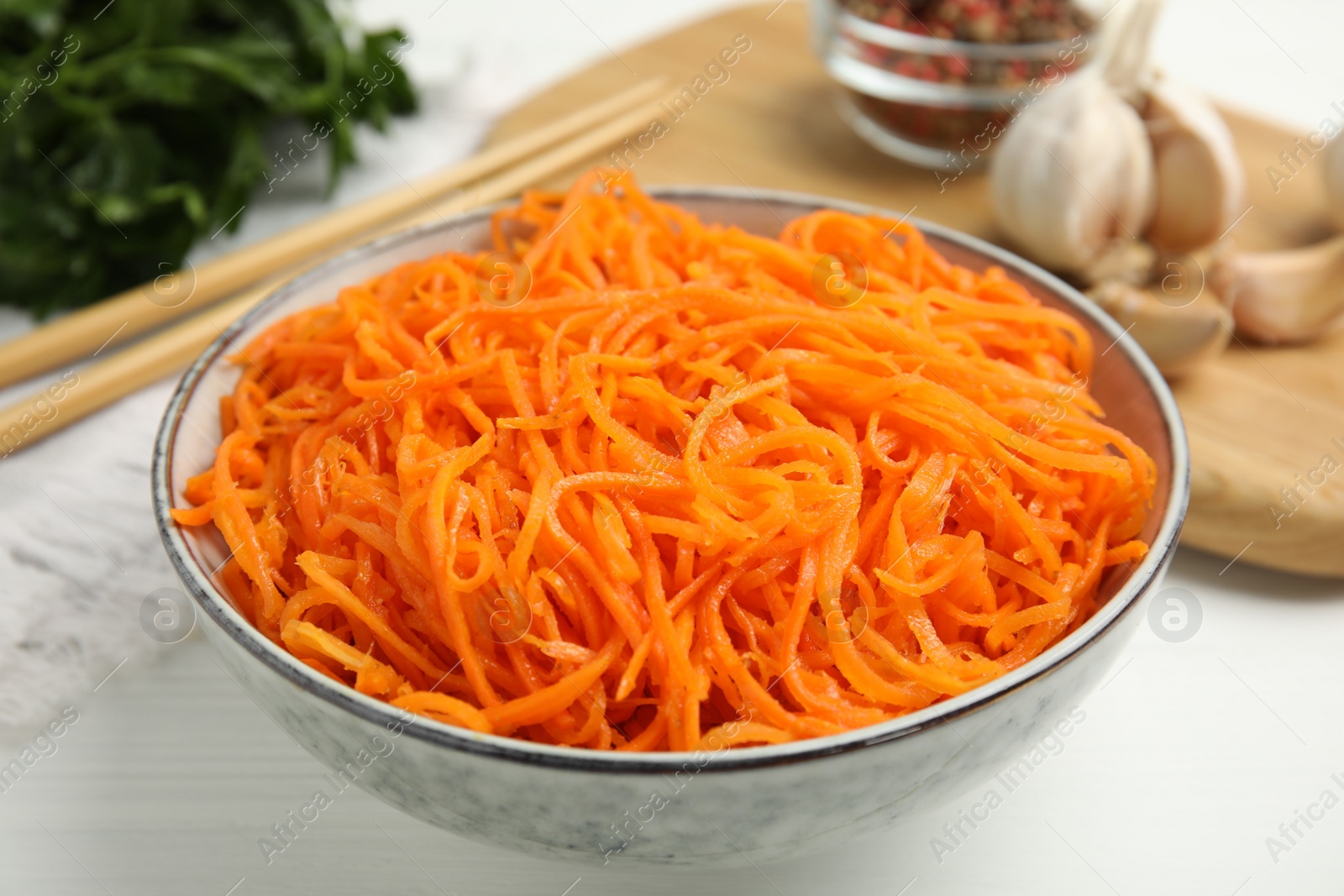 Photo of Delicious Korean carrot salad in bowl on white wooden table